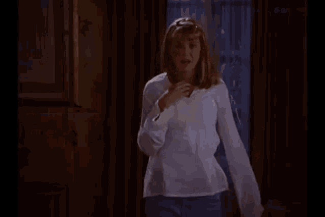 a woman in a white shirt stands in a room