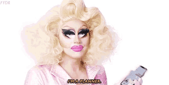 a drag queen is holding a cell phone and saying i 'm a planner .