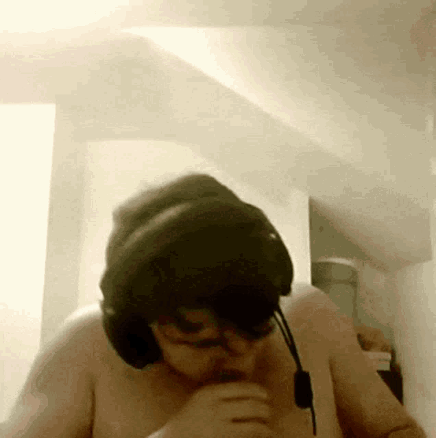 a man without a shirt is wearing headphones and glasses