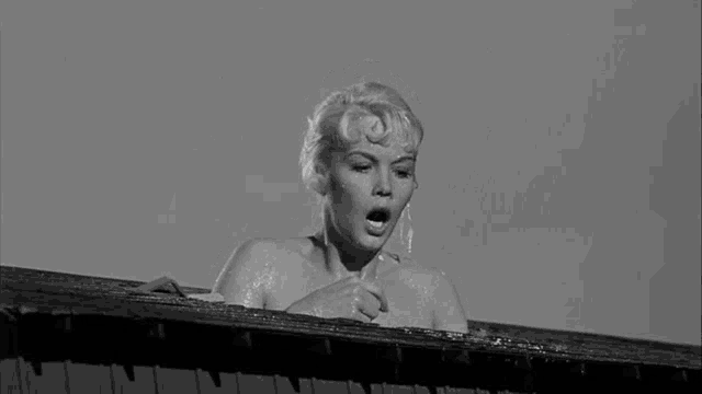 a naked woman is taking a bath on the roof of a building in a black and white photo .