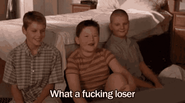 three young boys are sitting on a couch and one of them is saying what a fucking loser