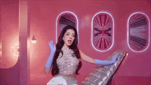 a woman wearing blue gloves is sitting on a chair in a pink room