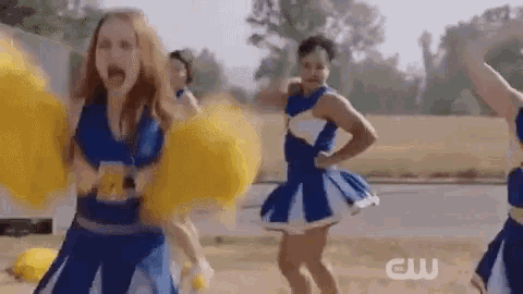 a group of cheerleaders in blue and white uniforms are cheering and holding yellow pom poms .