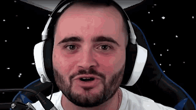 a man with a beard is wearing headphones and sitting in a chair .