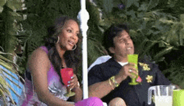 a man and a woman are sitting under an umbrella with drinks