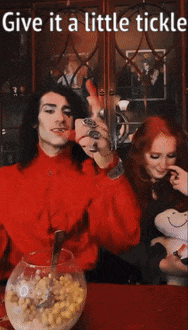 a man in a red shirt is giving a woman a little tickle with a bowl of cereal