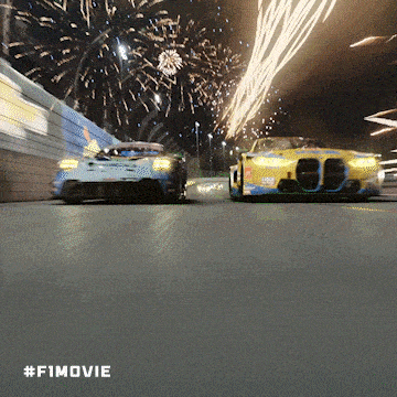 two cars are driving down a road with fireworks in the background and #f1movie written on the bottom
