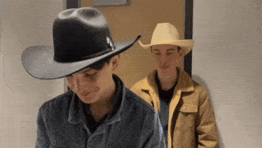 a man wearing a cowboy hat stands next to another man