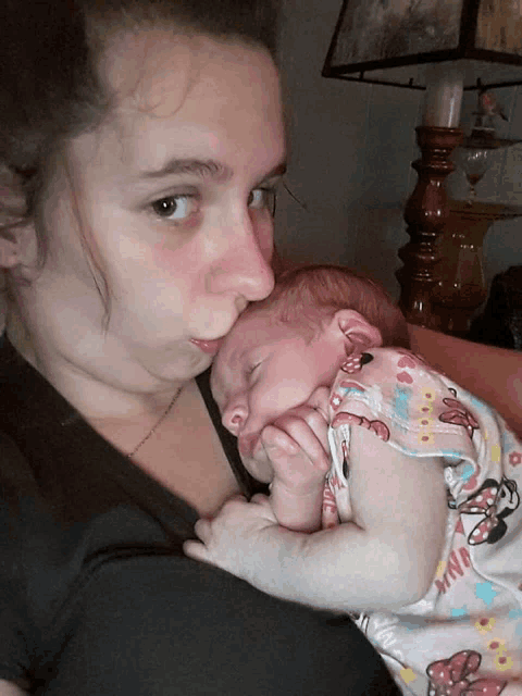 a woman holding a baby in a minnie mouse outfit