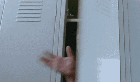 a man in a suit and tie is sticking his head out of a locker .