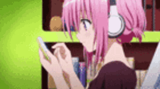 a pink haired anime girl wearing headphones is looking at her phone .