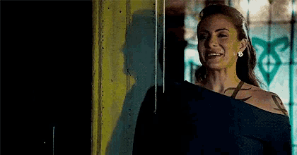 a woman with a tattoo on her shoulder is smiling in front of a window .