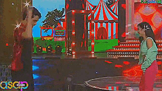 a man and a woman are dancing on a stage in front of a colorful background that says asco