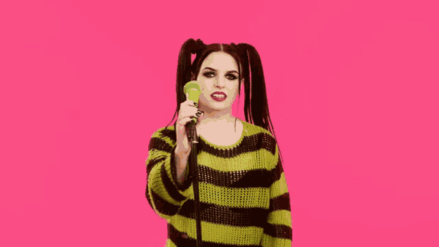 a woman in a green and black striped sweater sings into a green microphone