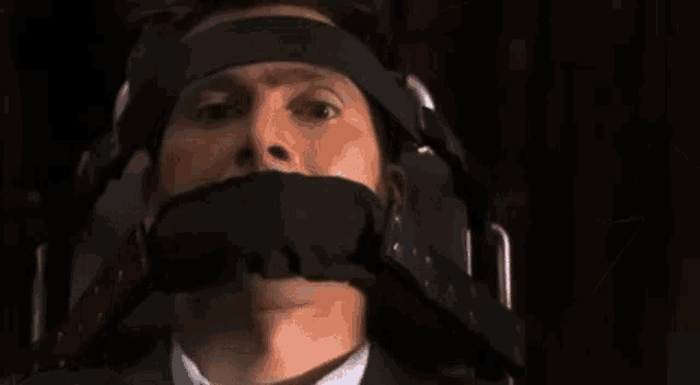 a man in a suit and tie is tied up with a bandage on his mouth .