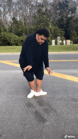a man in a black shirt and shorts is standing on a street with a tiktok watermark on the bottom right