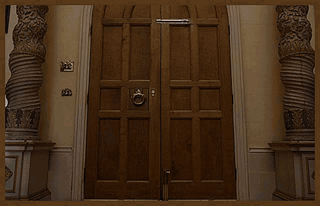 a man in a brown coat walks through a doorway