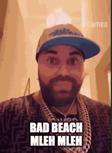 a man with a beard wearing a hat and chains says bad beach mleh mleh .