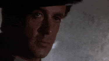 a close up of a man 's face wearing a hat and looking at the camera .