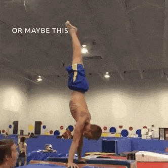 a man is doing a handstand on a bar in a gym .