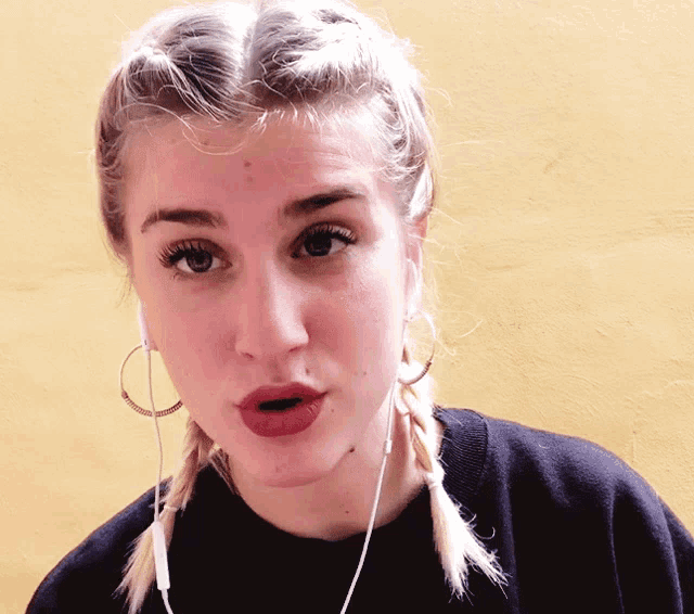 a woman wearing braids and hoop earrings is making a face