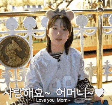 a girl wearing a bear headband says " love you mom " in korean