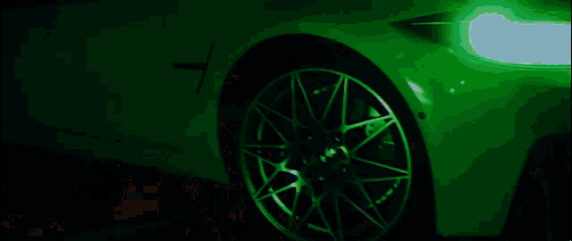 a close up of a green car 's wheel with a green background