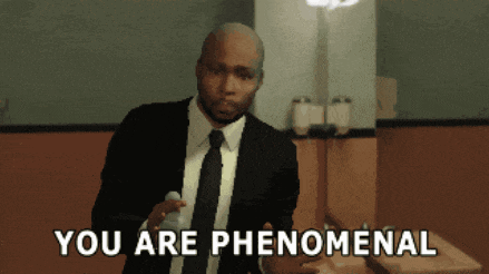 a man in a suit and tie is holding a microphone and says you are phenomenal