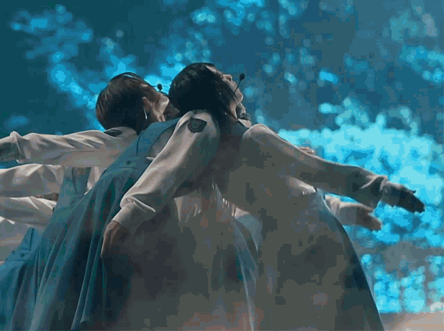 a group of people are dancing in a dark room with their arms outstretched