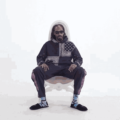 snoop dogg is sitting in a chair wearing sunglasses