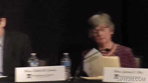 a woman sits at a table with a sign that says gifrun.com on it