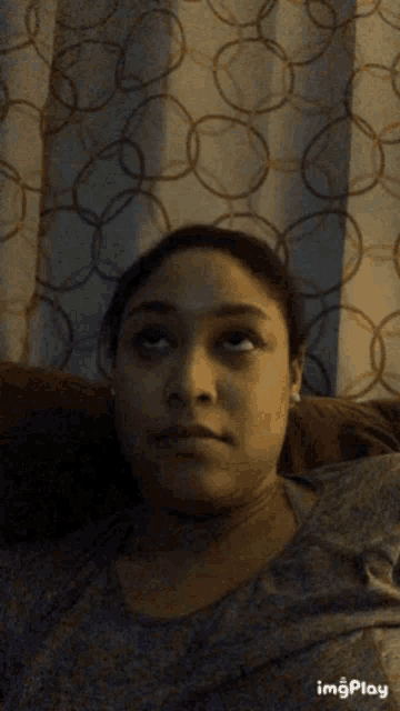 a woman is sitting on a couch and making a funny face .