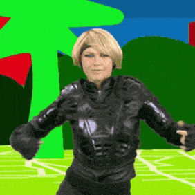 a woman in a black suit is dancing in front of a green tree