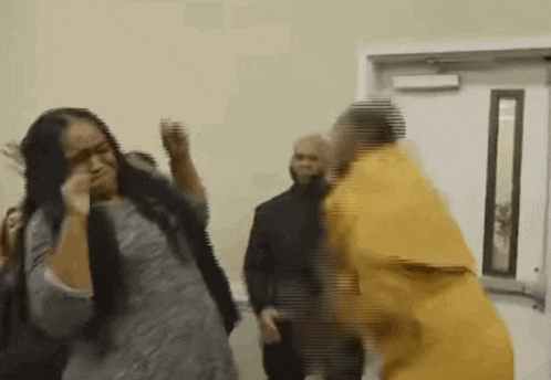 a man in a yellow prison uniform is standing next to a woman in a gray shirt .