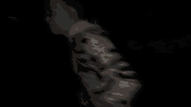 a blurry picture of a man in a camouflage jacket standing in the dark .