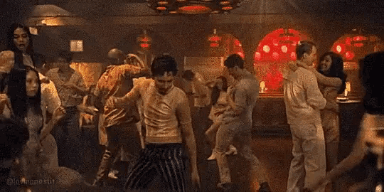 a group of people are dancing in a dark room in a bar .