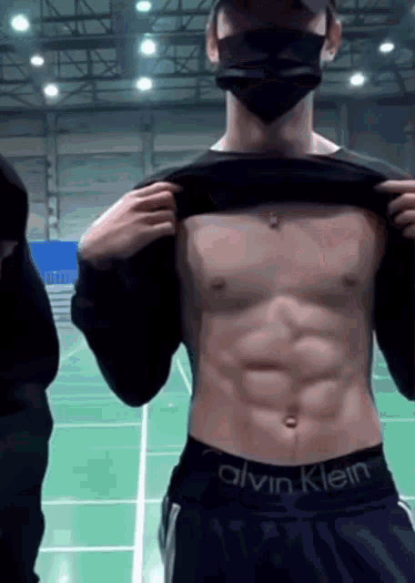 a man wearing a mask and calvin klein underwear shows off his abs