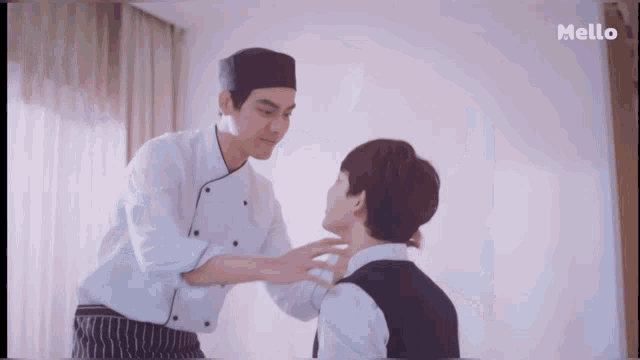 a man in a chef 's uniform is touching another man 's neck in a mello ad