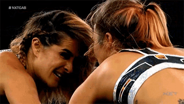 two female wrestlers are hugging each other in a wrestling ring .