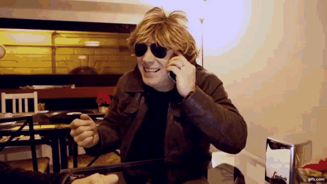 a man wearing sunglasses is talking on a phone
