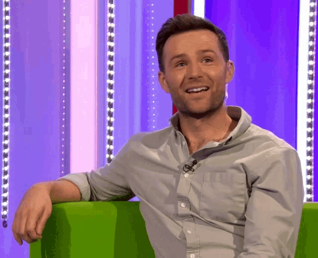 a man sitting in a green chair with a microphone on his neck