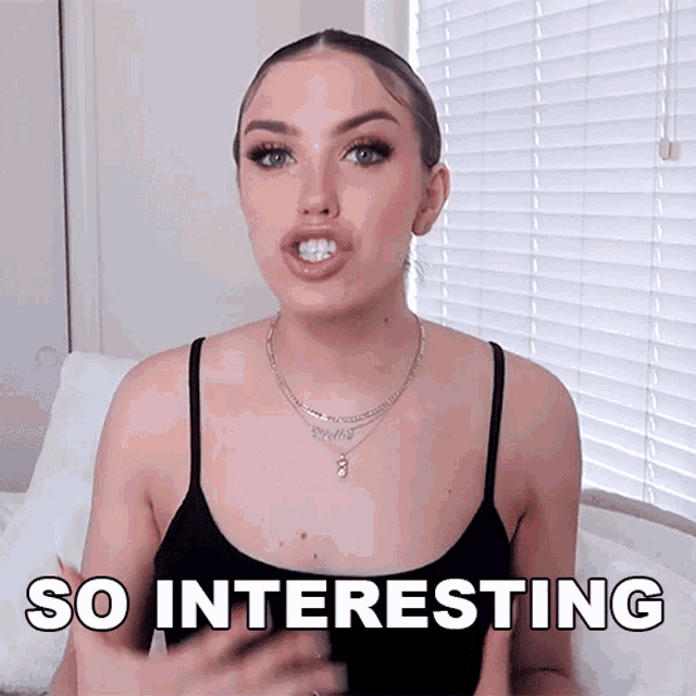 a woman in a black tank top says so interesting in front of a window