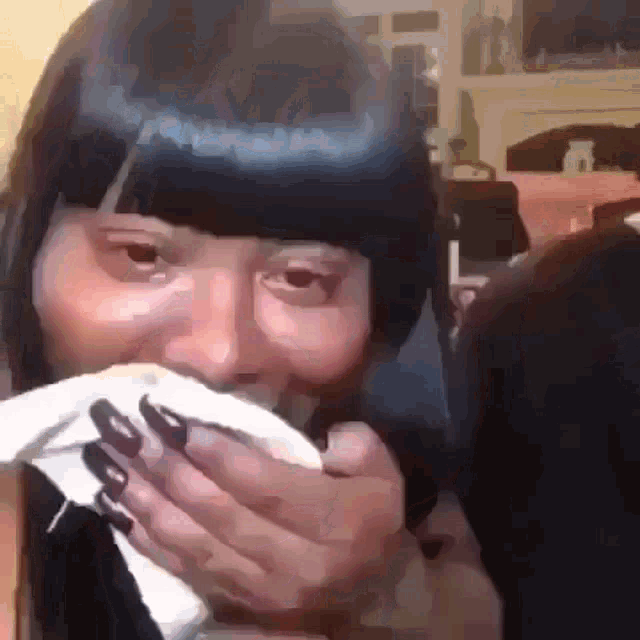 a woman with long nails is covering her mouth with a napkin .