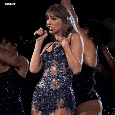 a woman in a blue dress is singing into a microphone .