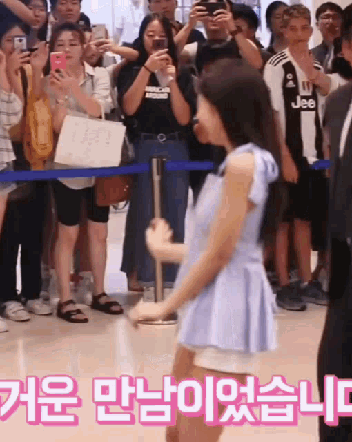 a girl in a blue dress stands in front of a crowd of people wearing jeep jerseys