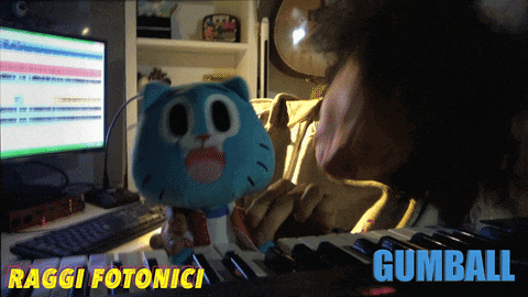 a person is playing a keyboard with a stuffed gumball behind them