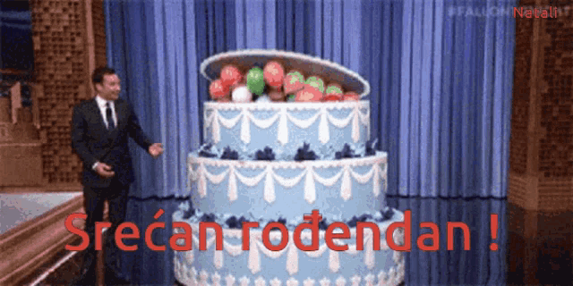 a man in a suit and tie is standing in front of a large cake that says srecan rodendan