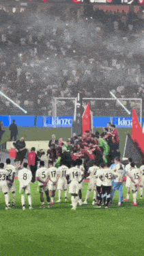 a group of soccer players are standing on a field with a king advertisement in the background
