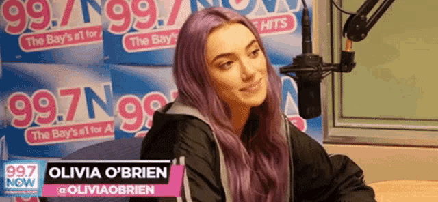 a woman with purple hair is sitting in front of a microphone in a radio studio