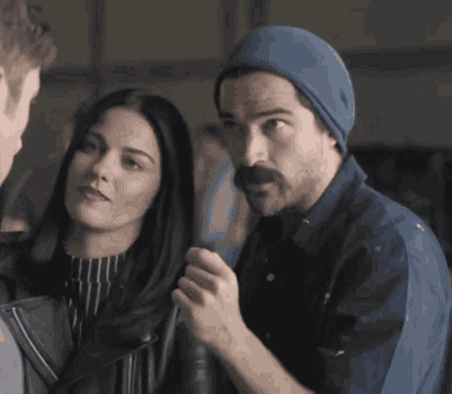 a man in a blue hat is talking to a woman in a black jacket